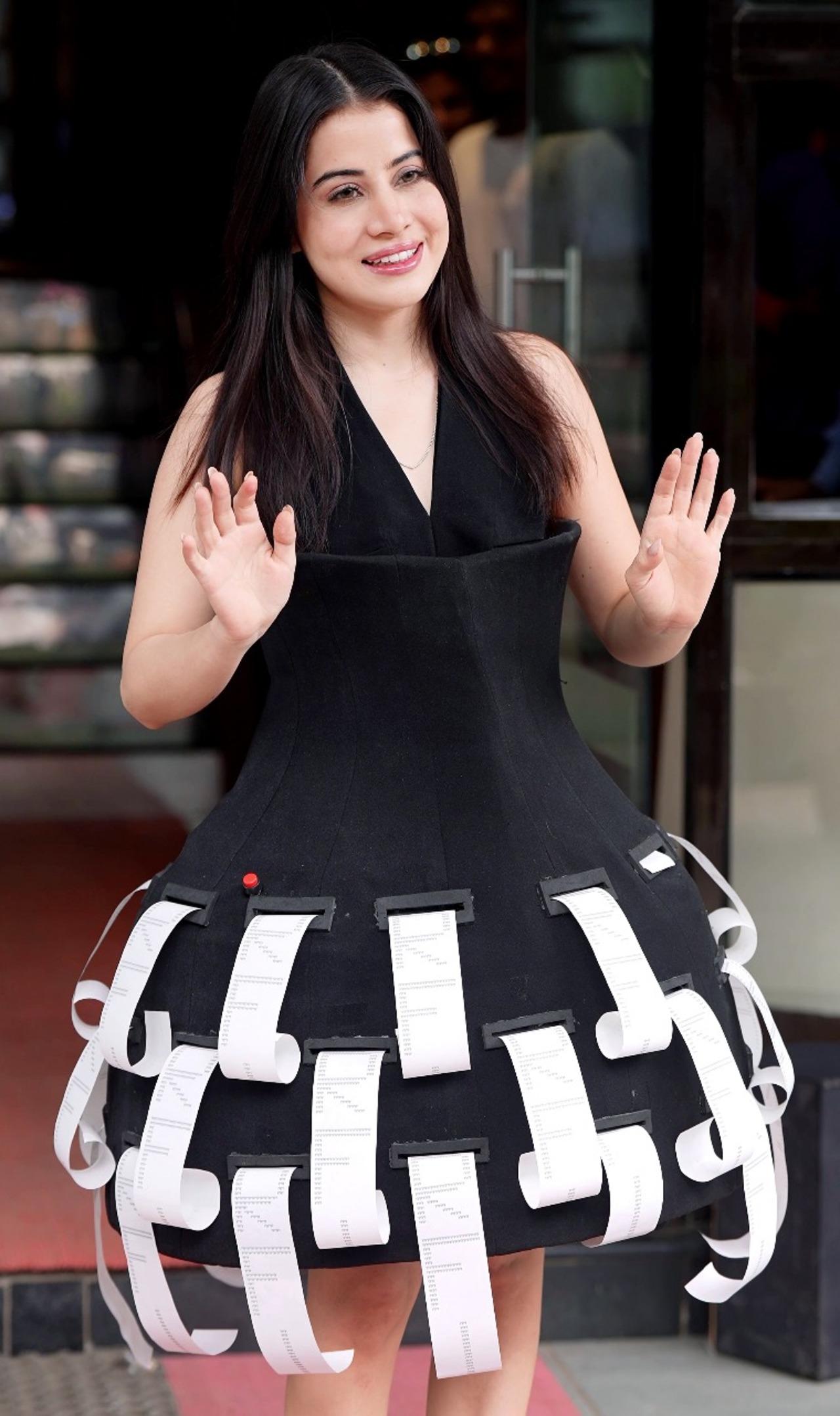 Urfi Javed has once again captured everyone’s attention with her latest appearance. She was seen in a shirt black dress. But what made her look unique was the paper rolls hanging from the skirt.